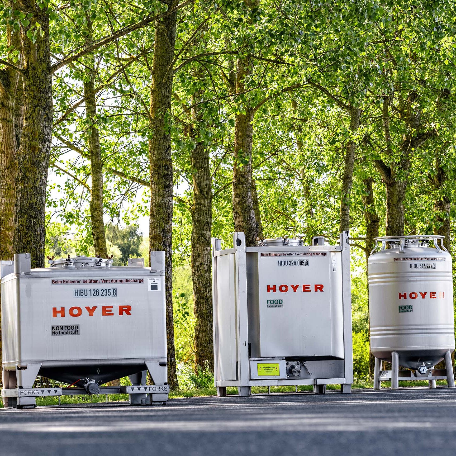 HOYER 标签的 IBC 容器沿小道排列,背景为绿地 贴有 HOYER 标签的 IBC 容器沿小道排列,背景为绿地