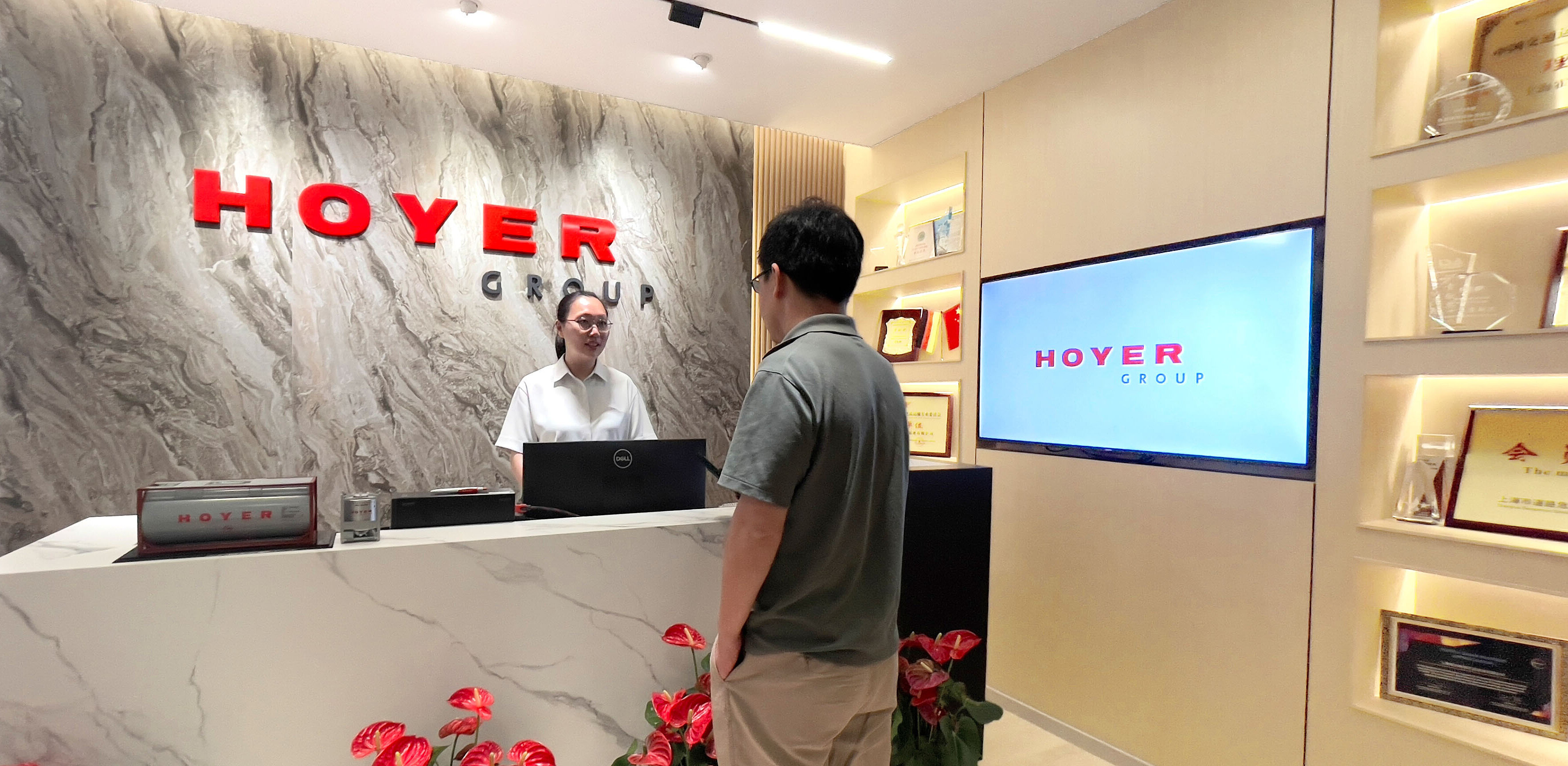 HOYER 集团中国办公区接待大厅，现代化的门厅设有品牌标识、大理石前台、红色鲜花和奖项展示
