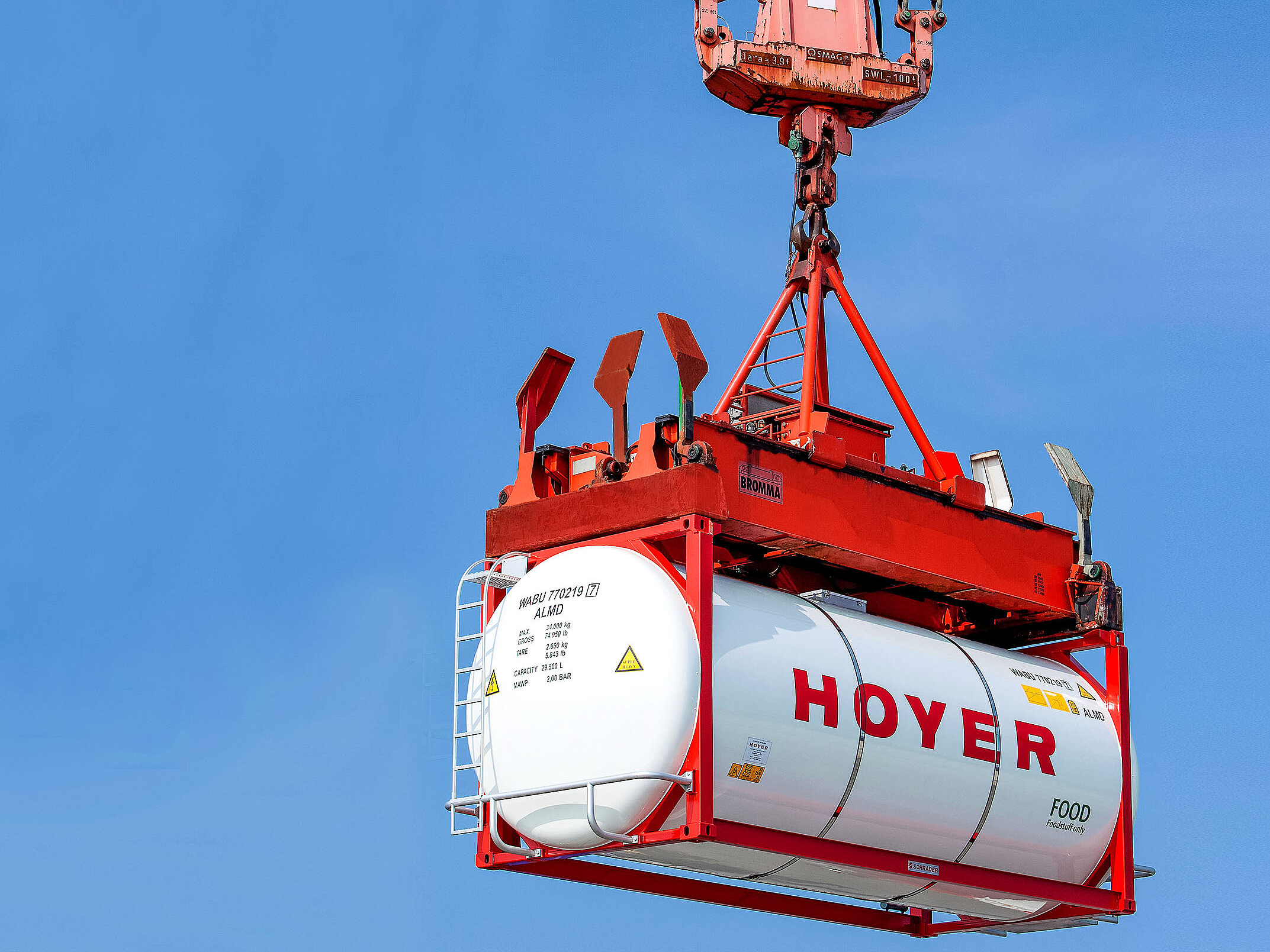 HOYER 食品 罐式集装箱 堆高机 堆场 HOYER 食品罐式集装箱在仓储区由堆高机搬运,背景为晴朗天空