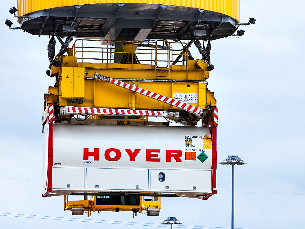 HOYER 气体 罐箱 起重机 危险 标签 光点 HOYER 气体容器贴有危险品标签,正在物流终端被黄色起重机吊装,起重机带红白安全条纹