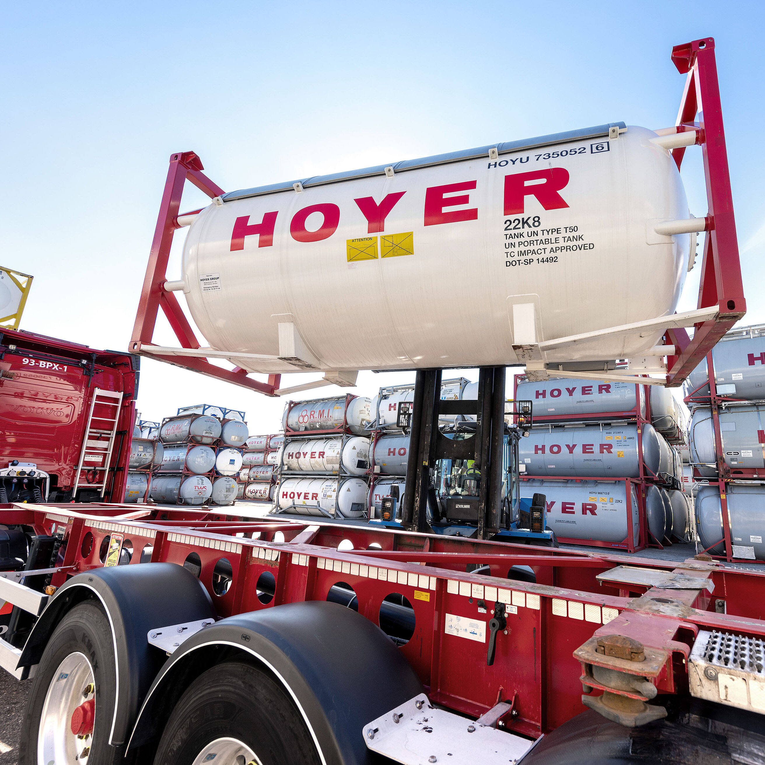 HOYER 堆高机 装载 气体 集装箱 码头 叉车在仓储区将 HOYER 气体罐式集装箱装上卡车底盘,背景为堆放的集装箱