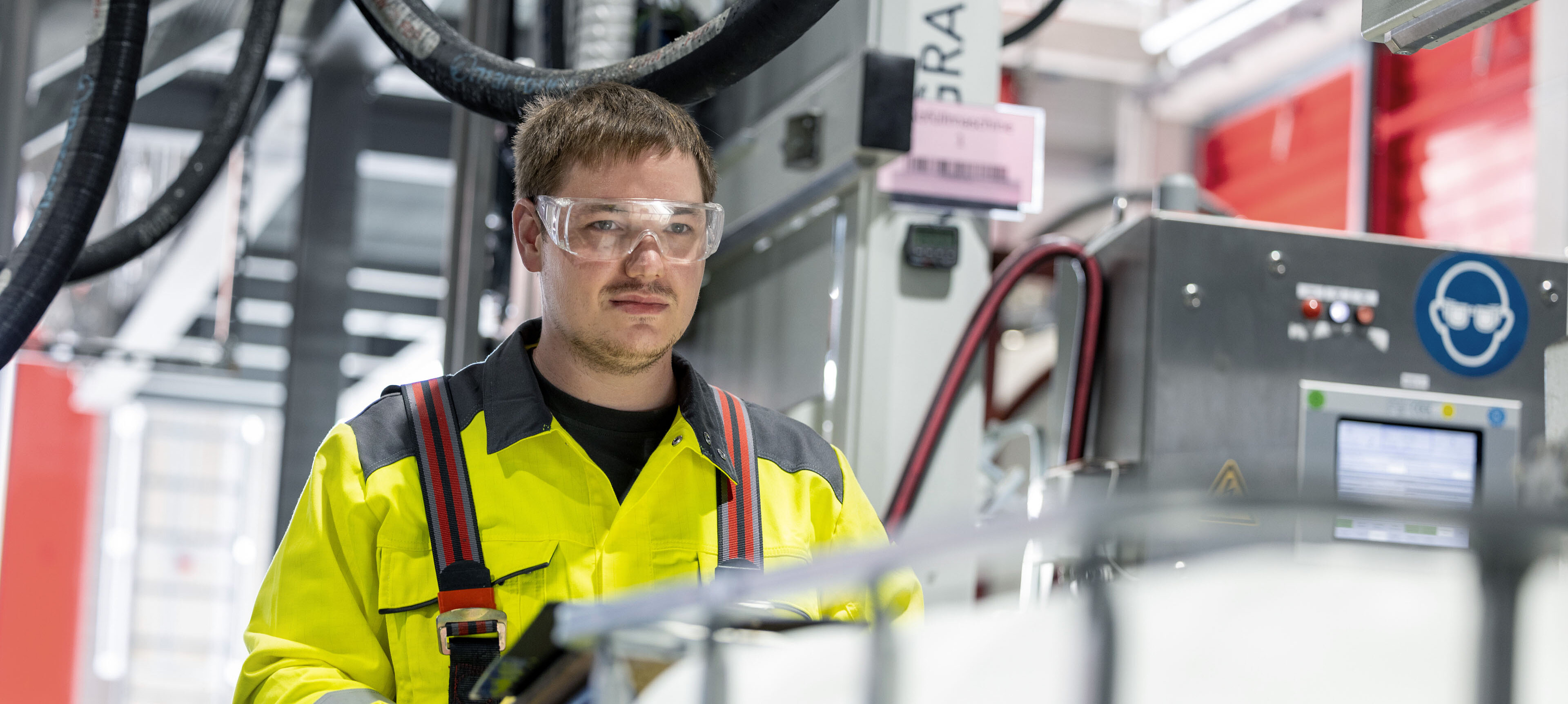 Employee in high-visibility jacket performing IBC filling in an industrial environment as part of HOYER SCS services