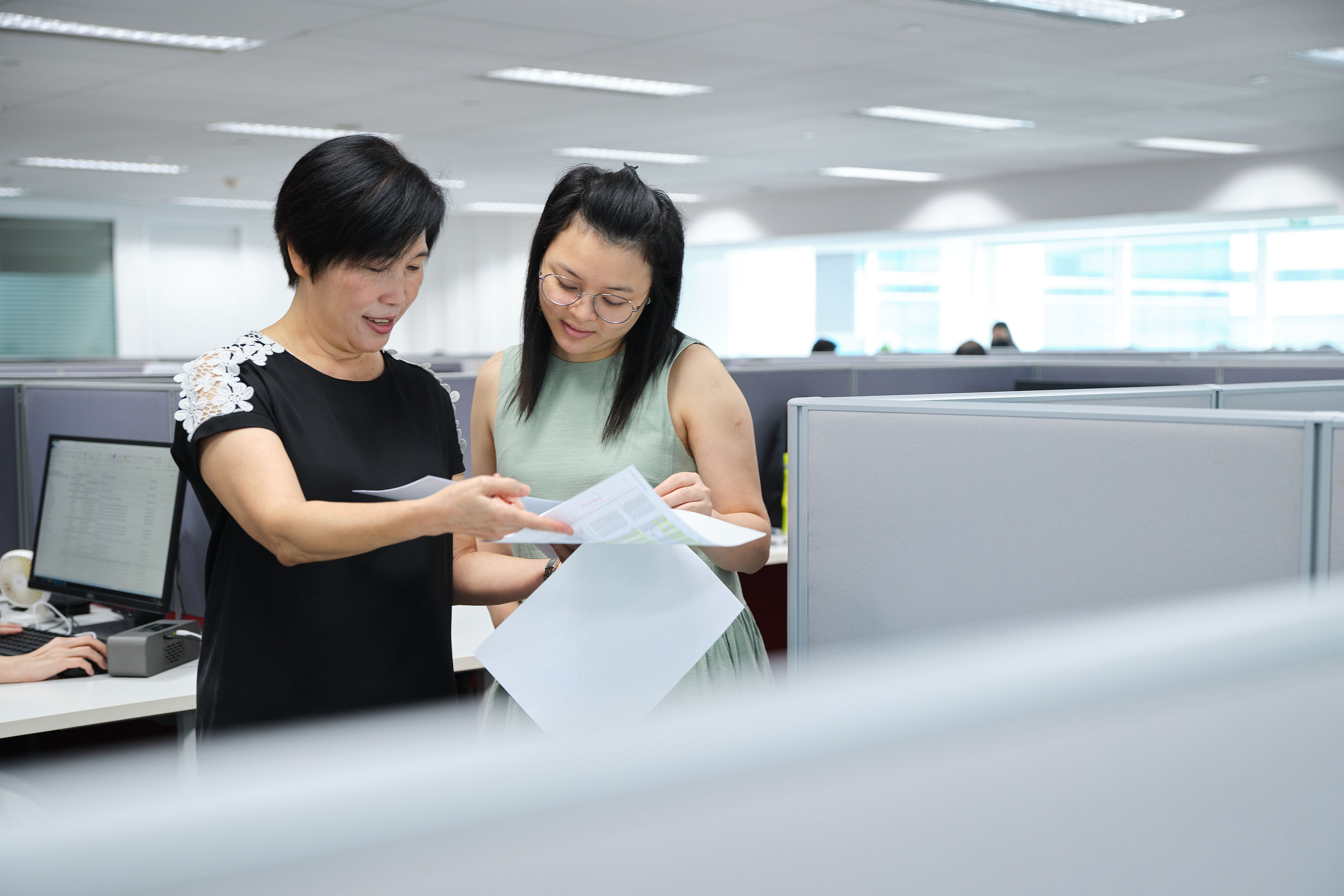HOYER 同事 讨论 办公室 文件 两位同事在现代办公室讨论文件,背景有办公桌、电脑及同事