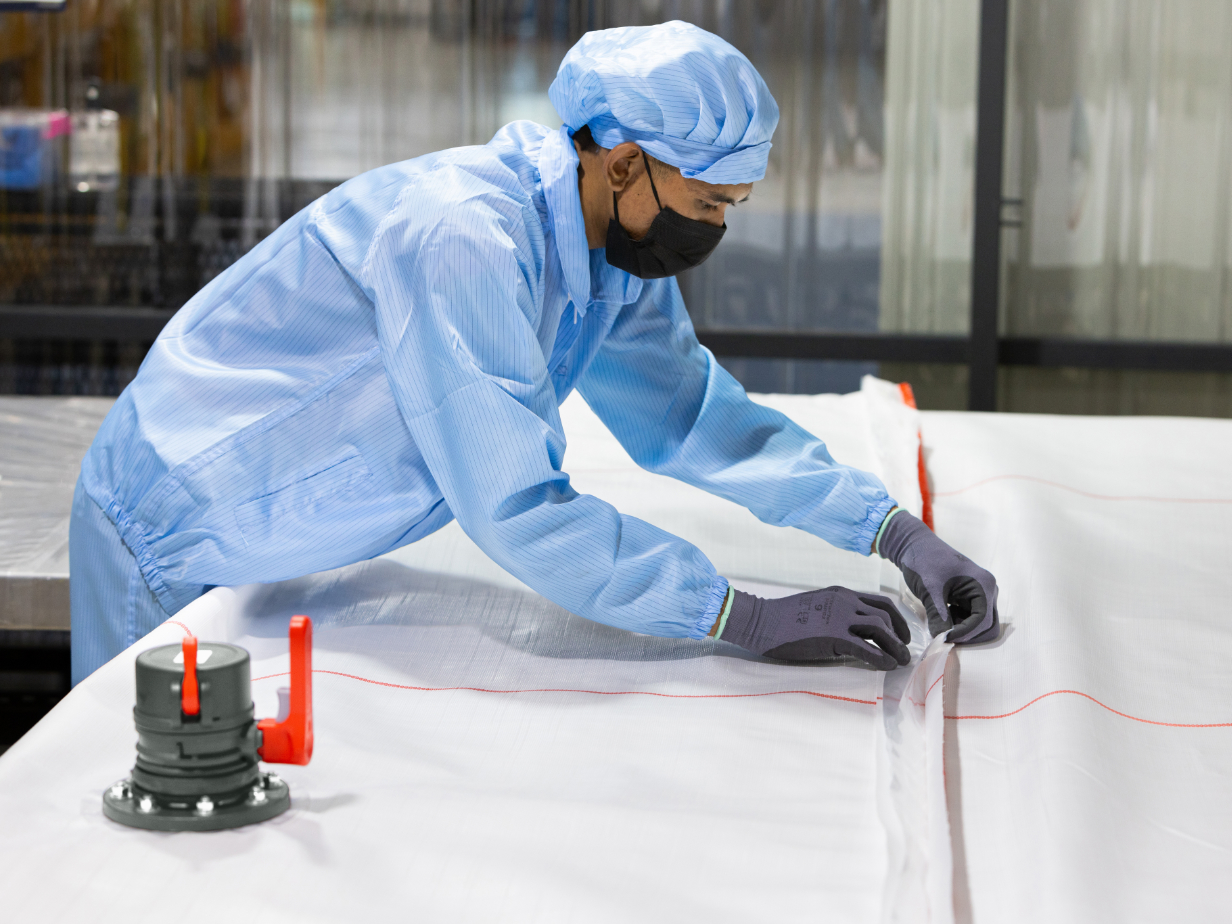 Employee in protective clothing working on a flexitank with valve in the lower part of the picture