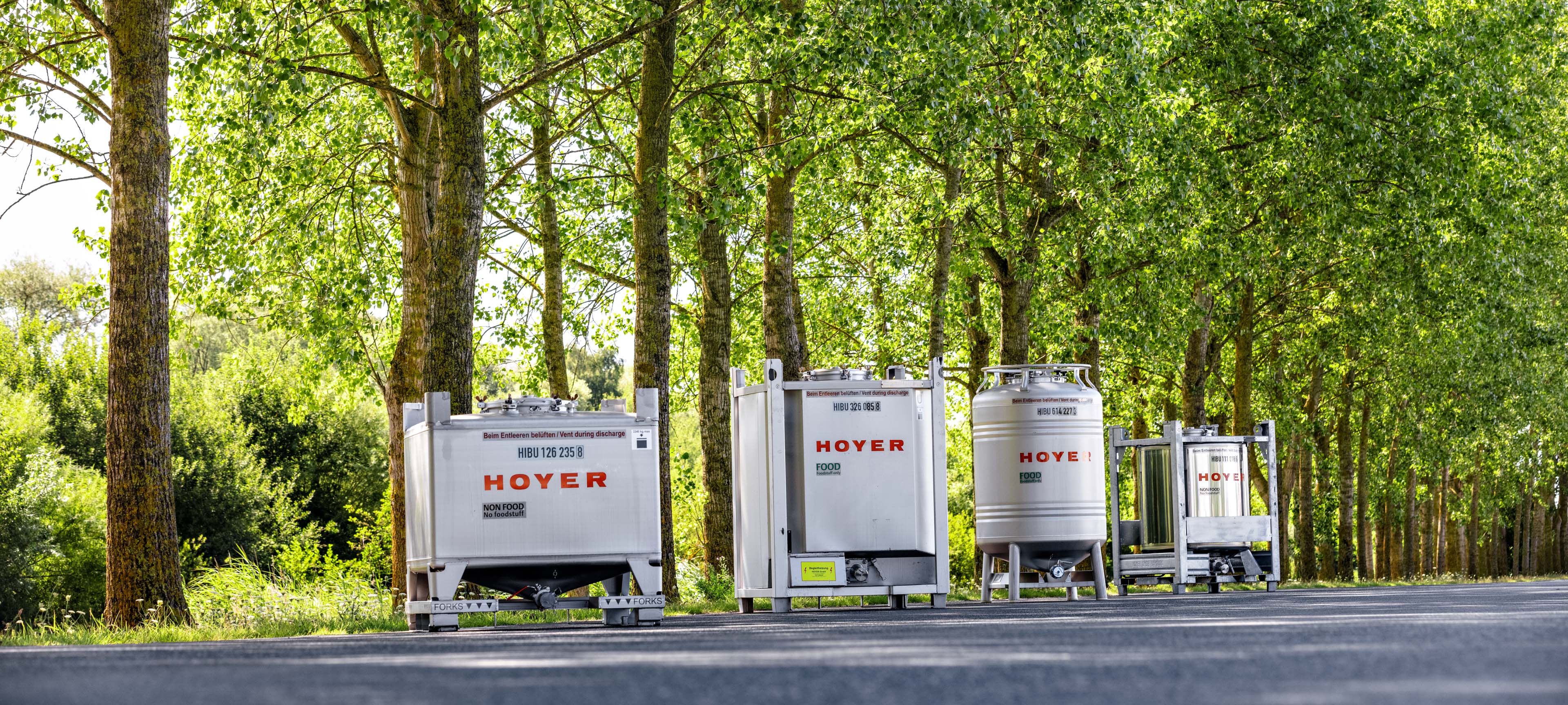 HOYER 标签的 IBC 容器沿小道排列,背景为绿地 贴有 HOYER 标签的 IBC 容器沿小道排列,背景为绿地