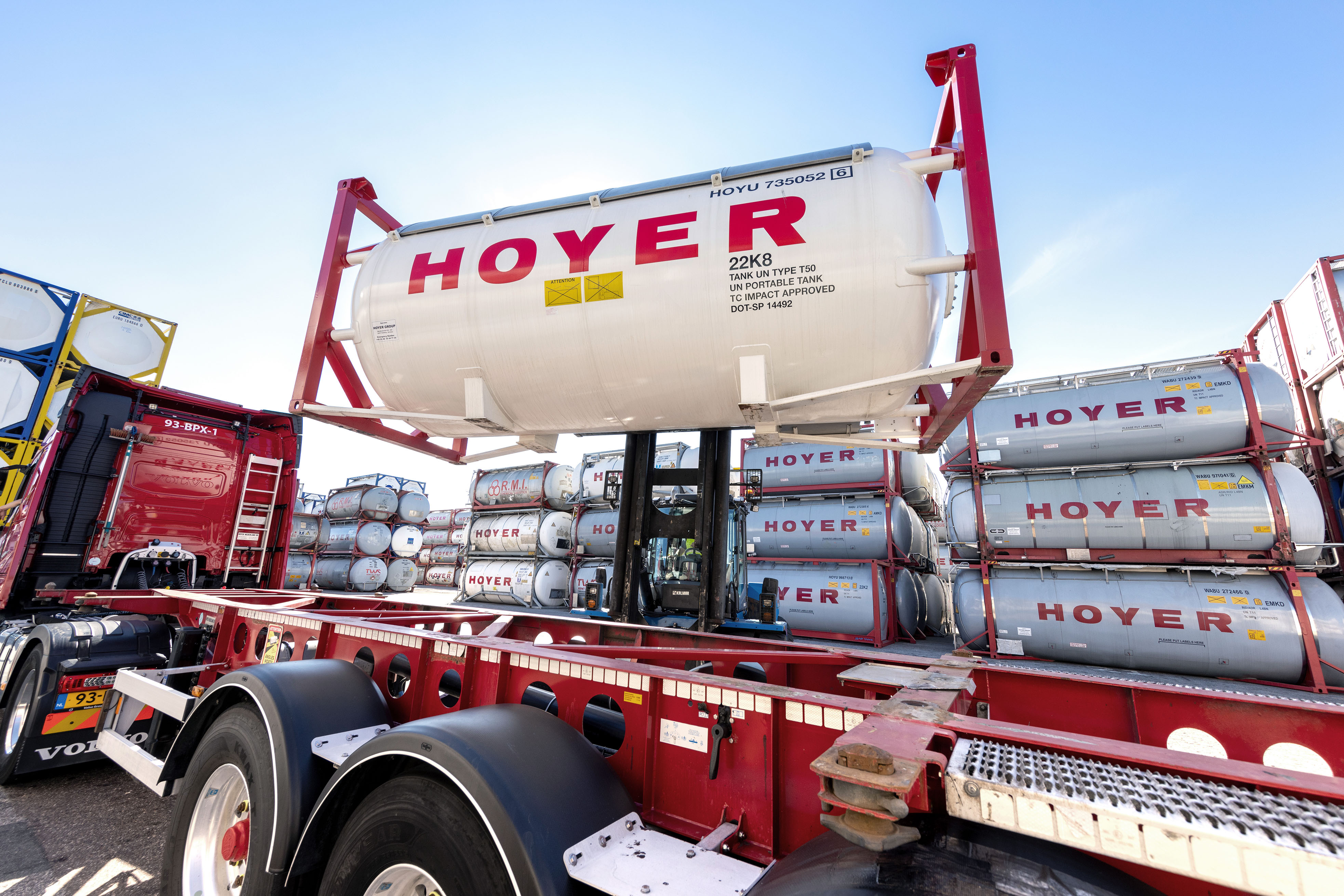 HOYER 堆高机 装载 气体 集装箱 码头 叉车在仓储区将 HOYER 气体罐式集装箱装上卡车底盘,背景为堆放的集装箱